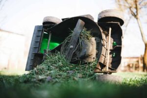 Lawn mower lying on grass clogged with clumps of wet grass in McKinney, TX